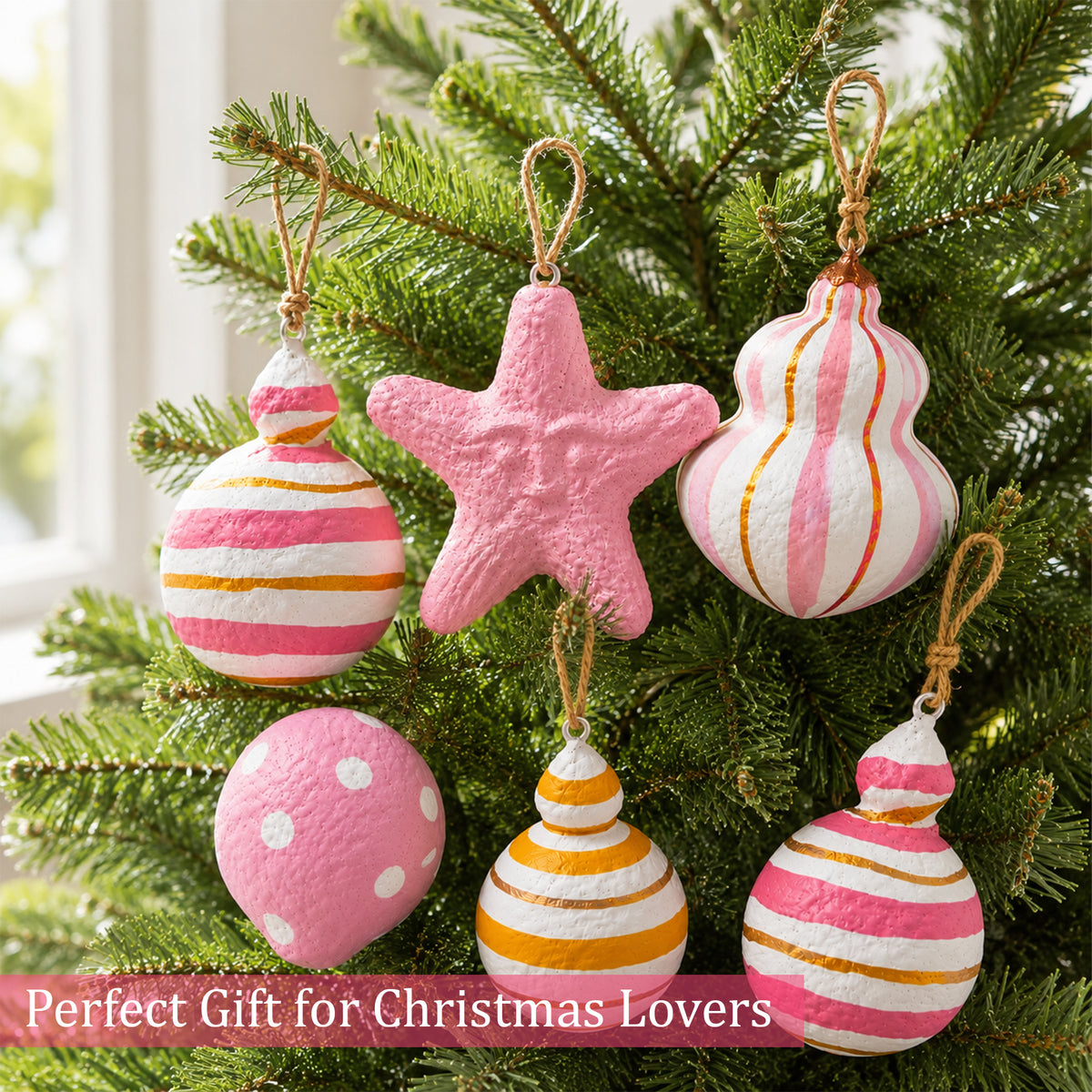 Pink and gold handmade Christmas ornaments hanging on a festive tree