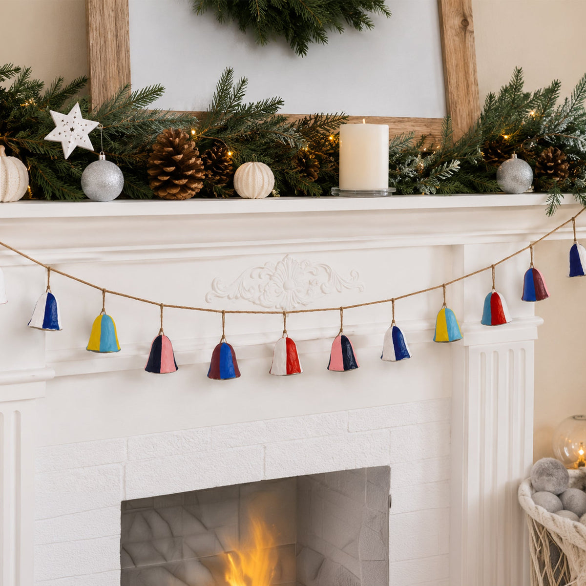 Bold colourful paper mache bell garland draped across white Christmas fireplace mantelpiece