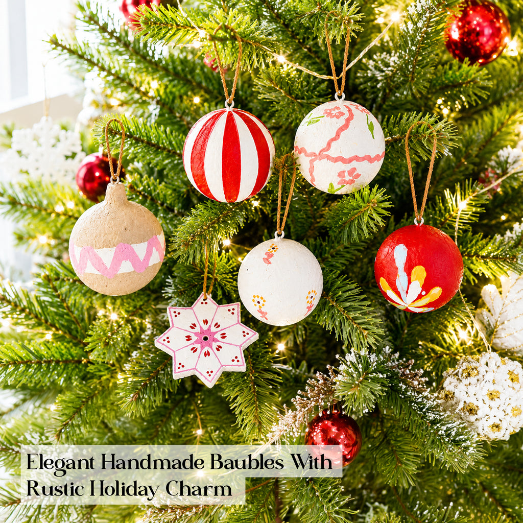 Artisan Christmas baubles hanging on decorated Christmas tree with fairy lights
