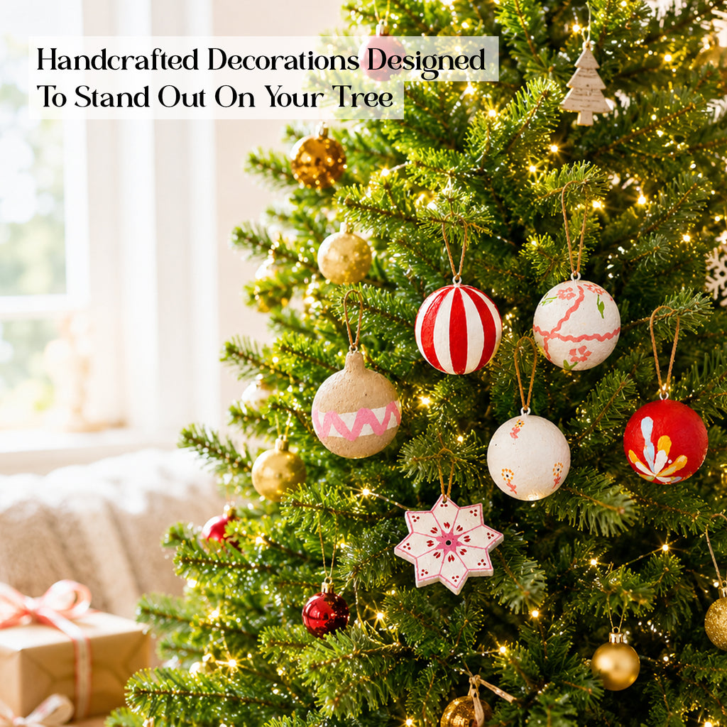 Handcrafted paper mâché Christmas tree ornaments set on lit Christmas tree UK
