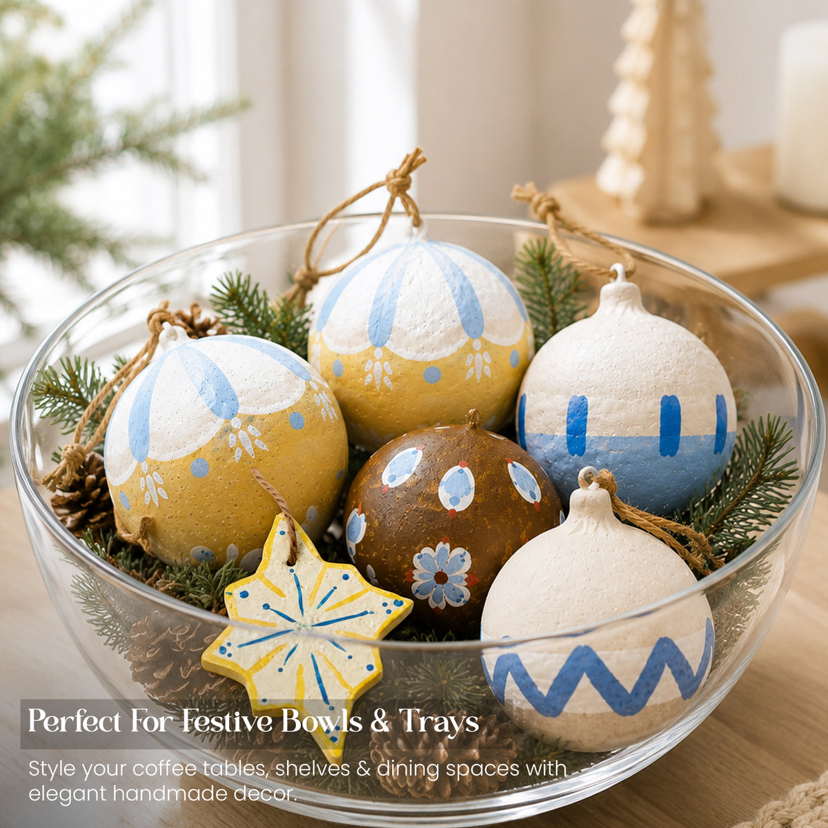 Handmade paper mache Christmas baubles in glass bowl with pine cones as festive table centrepiece decoration