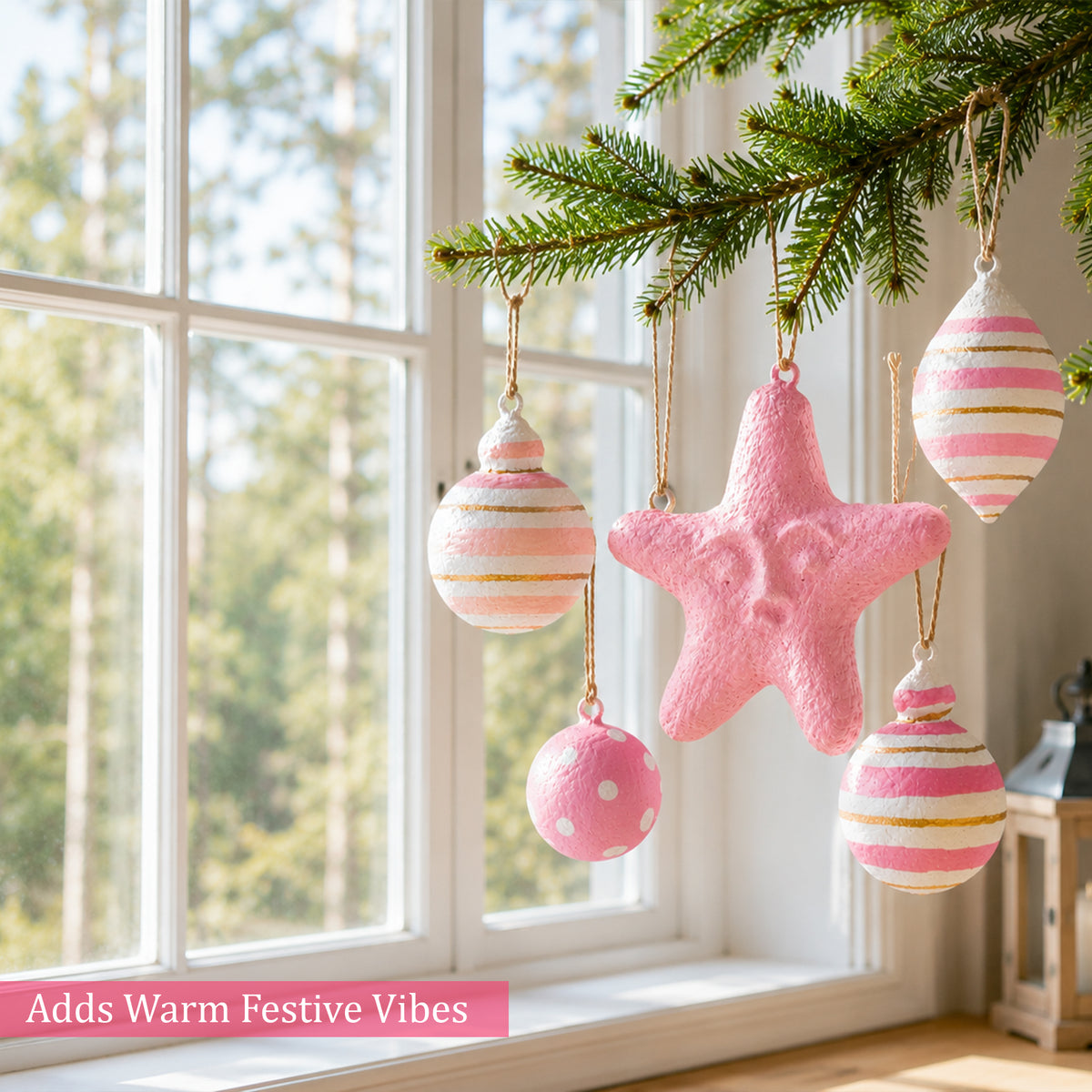 Handmade pink baubles and star ornament displayed by a window