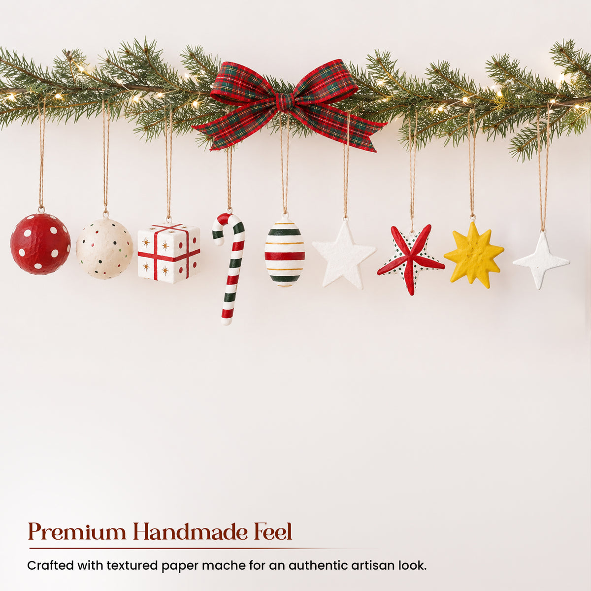All 9 handmade paper mache Christmas ornaments displayed in line under pine garland