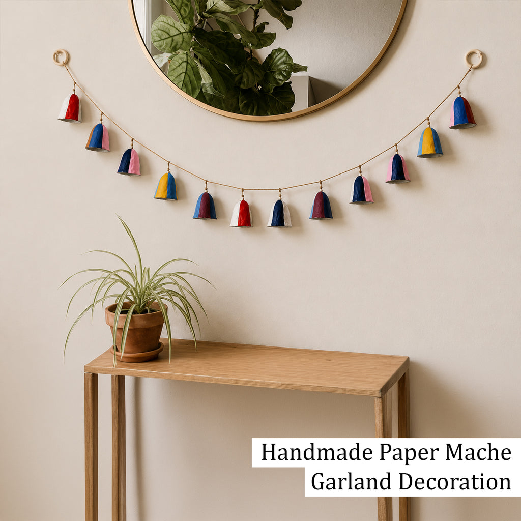 Handmade paper mache bell garland wall decoration above hallway console table UK home