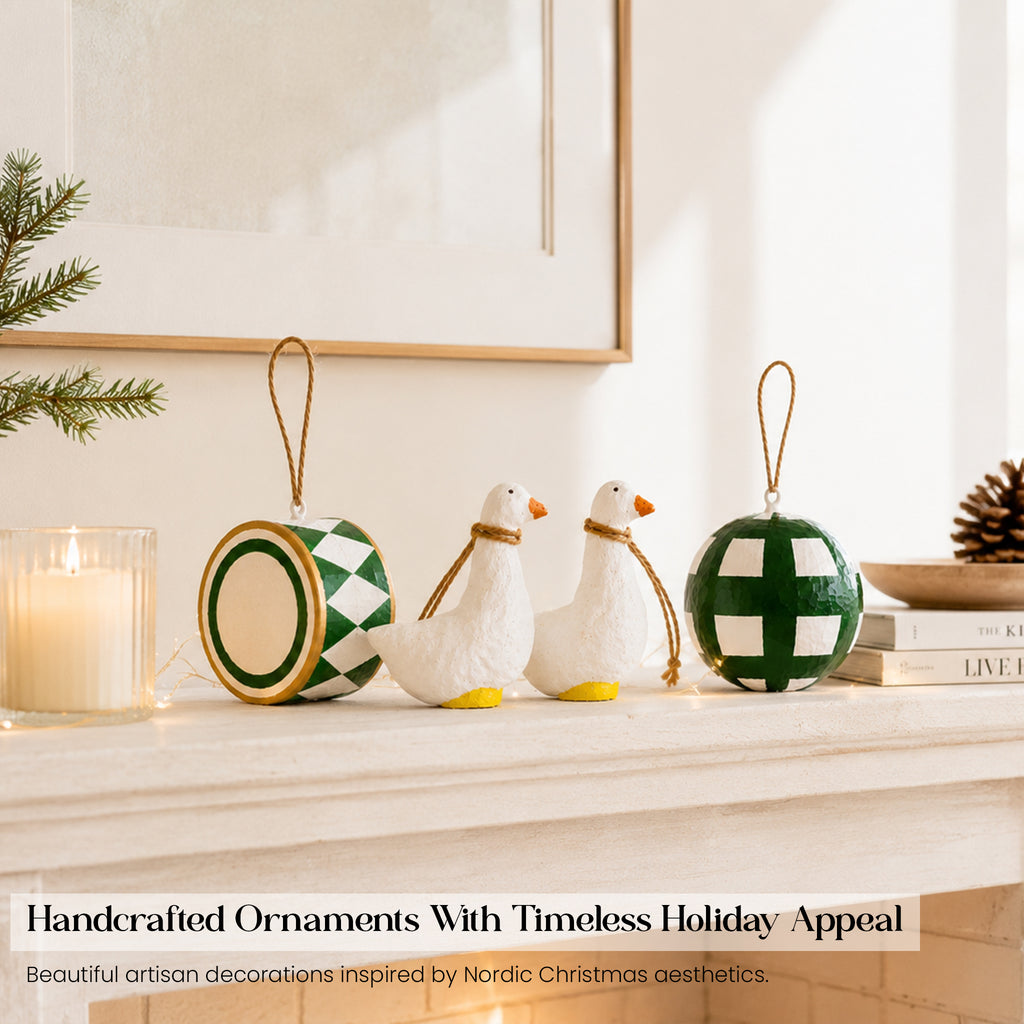 Handmade paper mache goose figurines green drum and bauble Christmas ornament set styled on white fireplace mantelpiece with candle