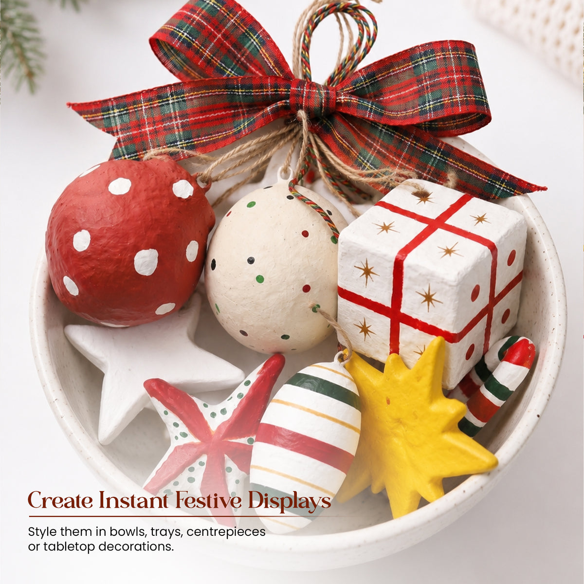 Handmade paper mache Christmas ornament set styled in white ceramic bowl as festive centrepiece