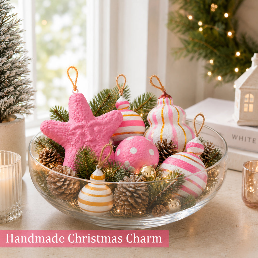 Blush pink and gold Christmas baubles arranged with pinecones and fairy lights