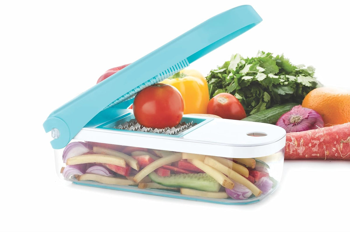 The dicer with its lid raised, a tomato resting on a blade insert and cut vegetable strips in the clear container