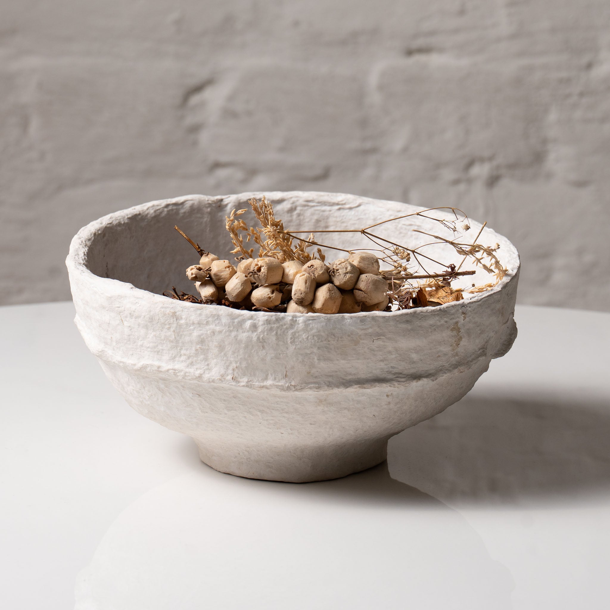 Textured papier-mâché decorative bowl styled with dried botanicals