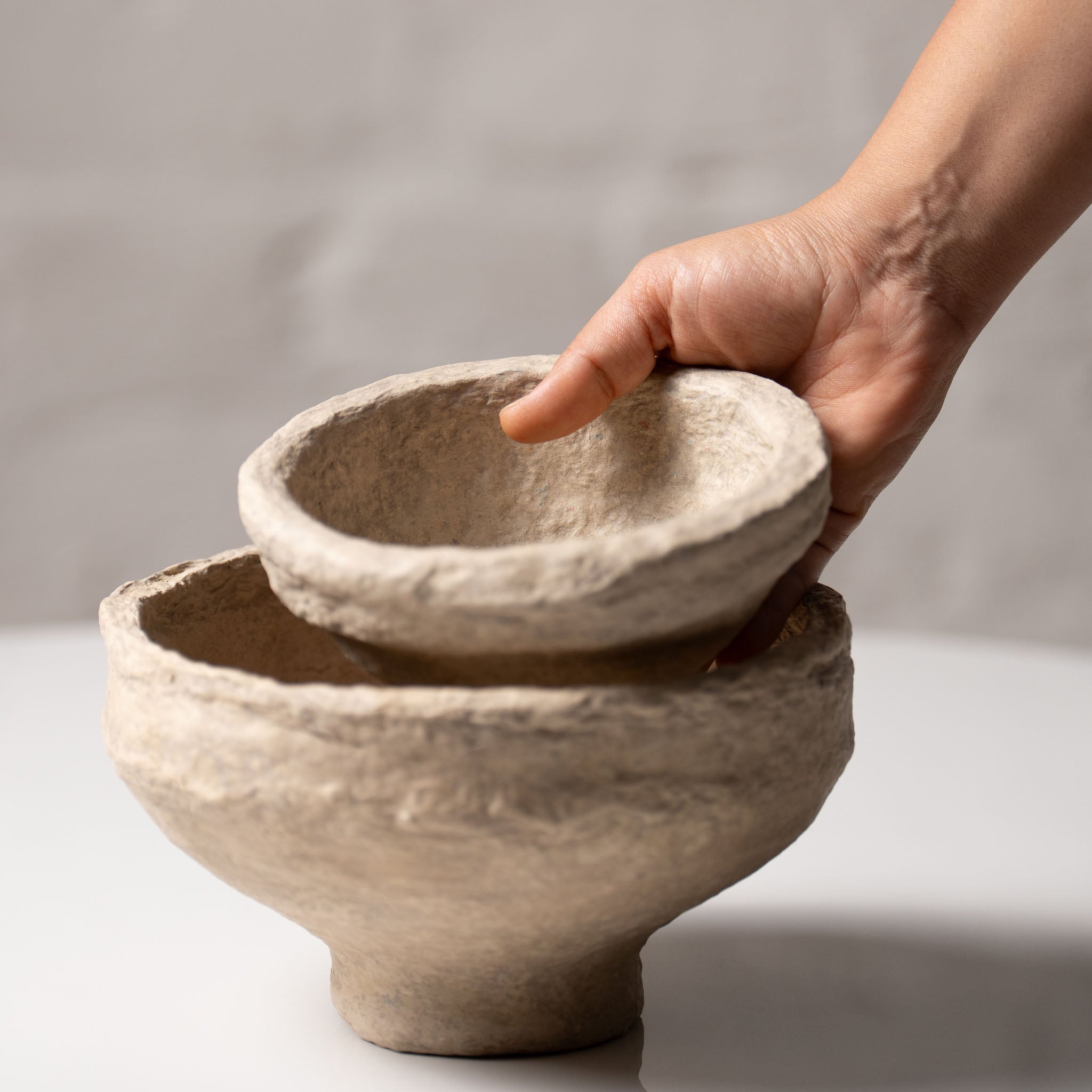 Hand holding handmade paper mache bowl showing size and texture, artisan crafted home decor