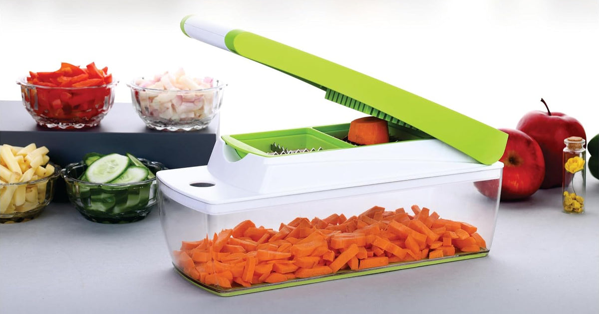 Chopper with the lid raised and a piece of carrot on the grid, with the clear container full of diced carrot